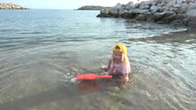 GRAND JUNCTION COLORADO-2017: Little Girl Plays Alone By The Shore – Scoops Sand