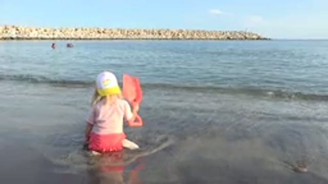 GRAND JUNCTION COLORADO-2017: Blond Child Sitting on Shore Playing with Bone