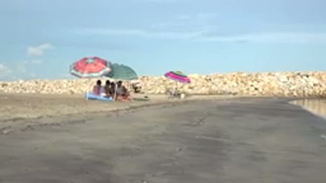 GRAND JUNCTION COLORADO-2017: People On Beach Sitting On The Shore With Umbrellas
