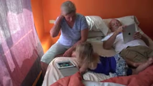 GRAND JUNCTION COLORADO-2017: Two People Sitting On Orange And White Bed Using Tablets