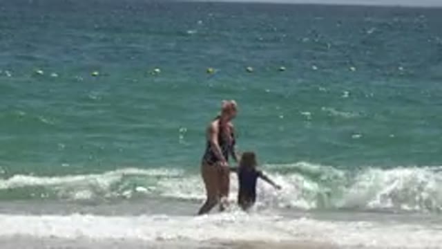 CABO SAN LUCAS MEXICO-2019: Little Girl Walks Through The Waves And Joins Her Mother