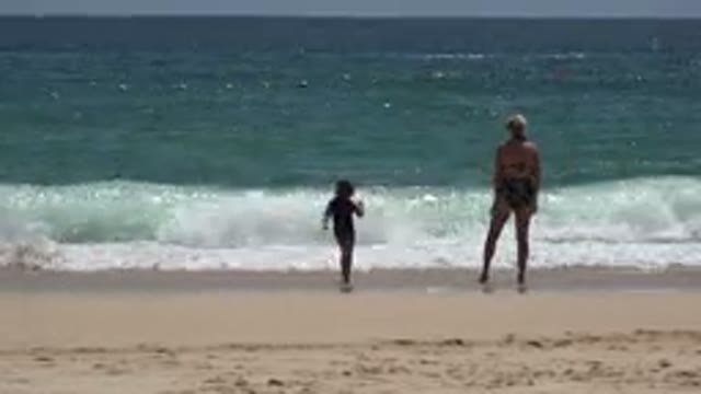 CABO SAN LUCAS MEXICO-2019: Kid Plays With Mother On Beach Near Sea In Sunny Day