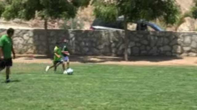 CABO SAN LUCAS MEXICO-2019: Two Young Children Play Soccer On Grass Field