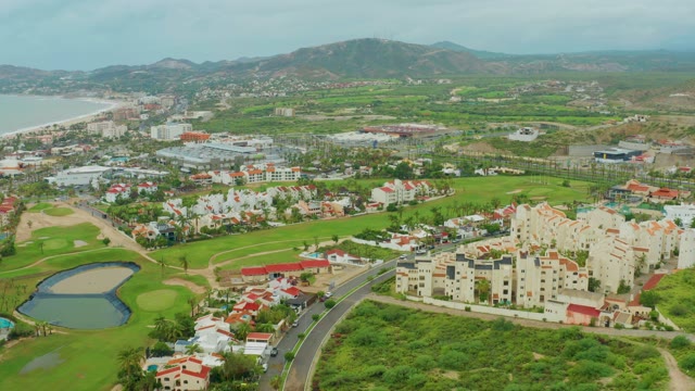 SAN JOSE DEL CABO BCS MEXICO-2021: Car Driving on Coastal Road near Golf Course and Buildings