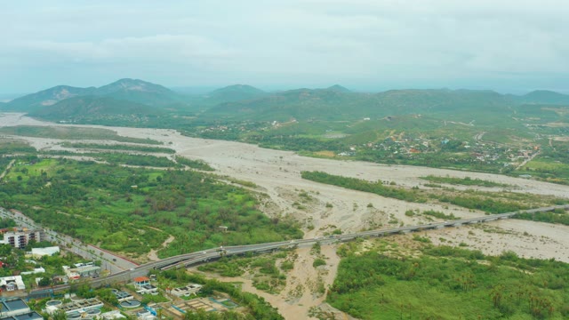 SAN JOSE DEL CABO BCS MEXICO-2021: Vehicles Moving Across River Bridge in Flooded Valley