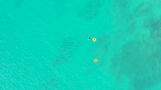 LAGUNA BEACH LOS CABOS BCS MEXICO-2021: People Floating with Yellow Floats in Turquoise Water