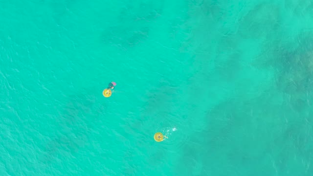 LAGUNA BEACH LOS CABOS BCS MEXICO-2021: People Floating on Yellow Rings in Turquoise Ocean