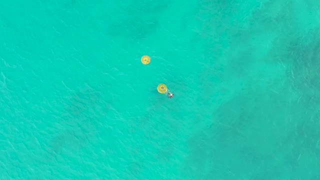 LAGUNA BEACH LOS CABOS BCS MEXICO-2021: A Person Floating on a Yellow Buoy in Clear Turquoise Water