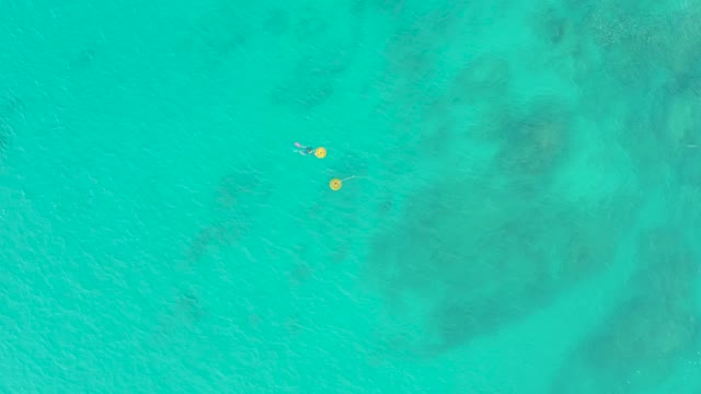 LAGUNA BEACH LOS CABOS BCS MEXICO-2021: Swimmer Moving Between Yellow Buoys in Clear Turquoise Water