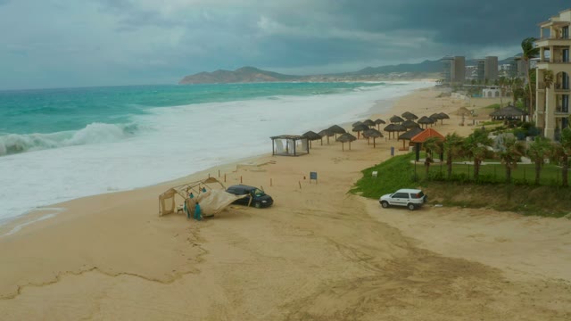 DREAMS RESORT LOS CABOS BCS MEXICO-2021: Ocean Waves Rolling Onto Sandy Shore with Thatched Umbrellas