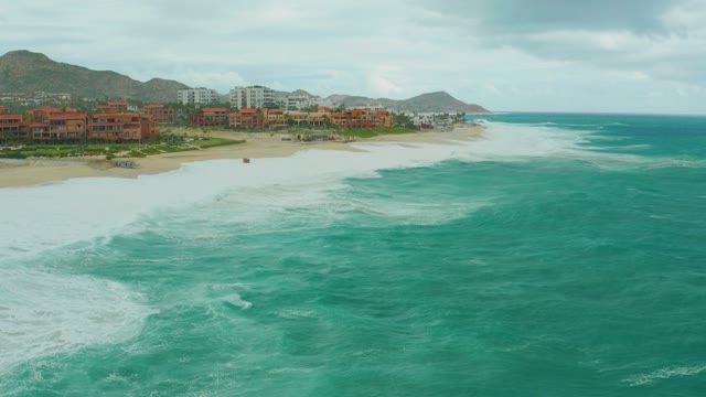 DREAMS RESORT LOS CABOS BCS MEXICO-2021: Waves Crashing on Sandy Beach with Coastal Buildings
