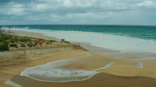 DREAMS RESORT LOS CABOS BCS MEXICO-2021: Waves Crashing on Sandy Shore with Cloudy Sky