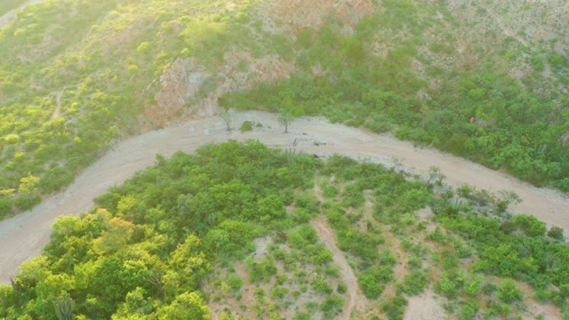 CABO PULMO BCS MEXICO-2021: Vehicle Traveling on Winding Dirt Road Through Green Hills