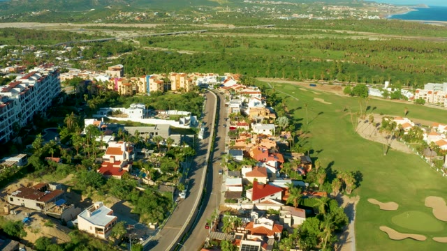 SAN JOSE DEL CABO BCS MEXICO-2021: Vehicles Moving Along Road Beside Golf Course and Buildings
