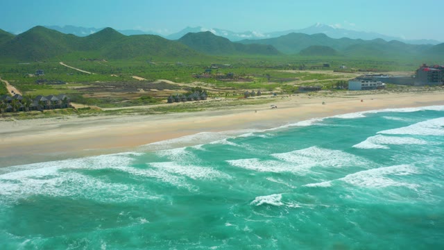 CERRITOS BEACH BCS MEXICO-2021: Waves Crashing on Sandy Beach with Distant Green Hills