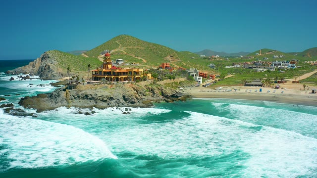 CERRITOS BEACH BCS MEXICO-2021: Waves Crashing Against Rocky Shore with Coastal Building