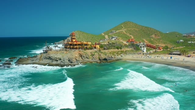 CERRITOS BEACH BCS MEXICO-2021: Waves Crashing Near Coastal Building on Rocky Shore