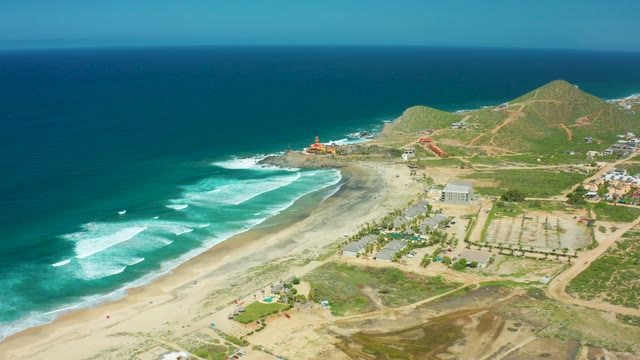 CERRITOS BEACH BCS MEXICO-2021: Waves Rolling Onto Sandy Shore with Coastal Buildings