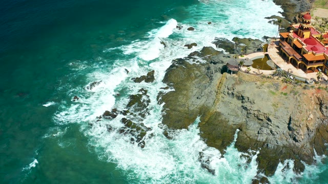 CERRITOS BEACH BCS MEXICO-2021: Waves Crashing Against Rocky Coastline with Cliffside Building