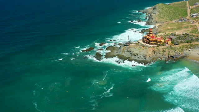 CERRITOS BEACH BCS MEXICO-2021: Coastal Waves Crashing on Rocky Shore Near Cliffside Building