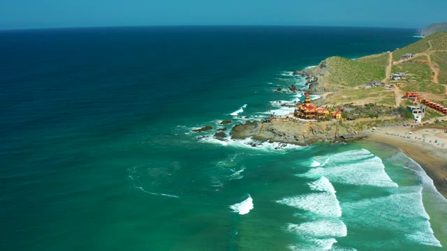CERRITOS BEACH BCS MEXICO-2021: Coastal Waves Breaking Near Rocky Headland with Buildings