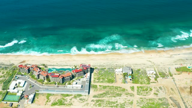 CERRITOS BEACH BCS MEXICO-2021: Ocean Waves Rolling Onto Sandy Beach with Buildings