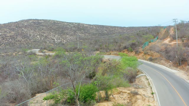 LA PLAYITA LOS CABOS MEXICO-2021: Car Driving on Winding Road Through Dry Hills