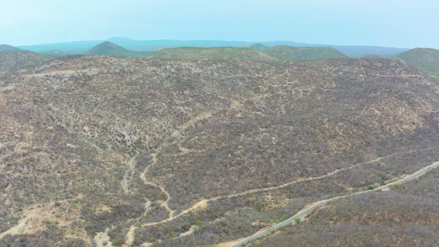 LA PLAYITA LOS CABOS MEXICO-2021: Vehicle Moving Along a Winding Road Through Dry Hills