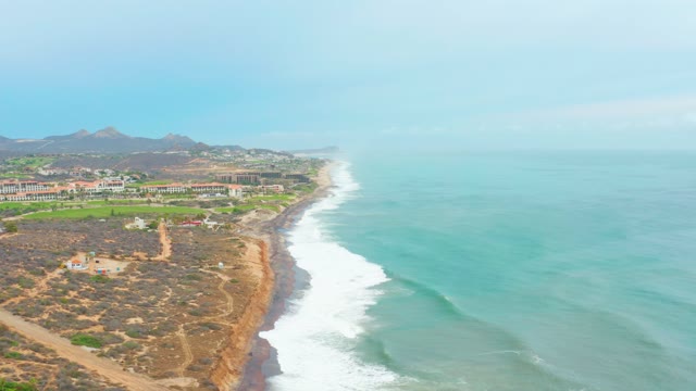 LA PLAYITA LOS CABOS MEXICO-2021: Coastal Hillside Road with Moving Vehicle and Ocean Waves