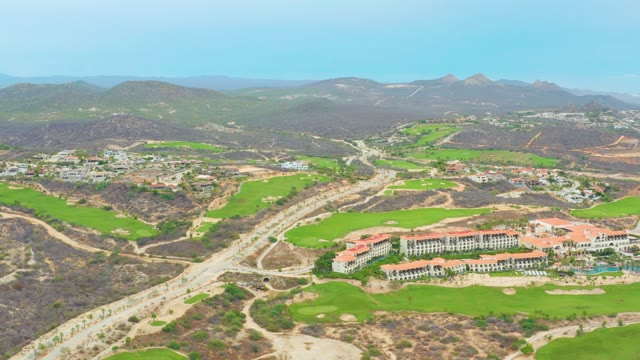 LA PLAYITA LOS CABOS MEXICO-2021: Winding Road Through Hilly Green Landscape with Buildings
