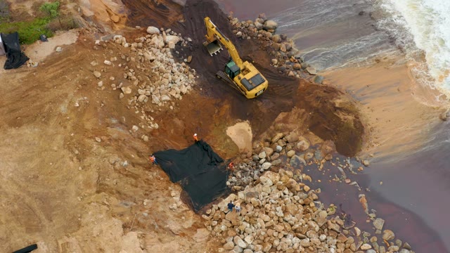 LA PLAYITA LOS CABOS MEXICO-2021: Excavator Operating on Muddy Riverbank with Rocks