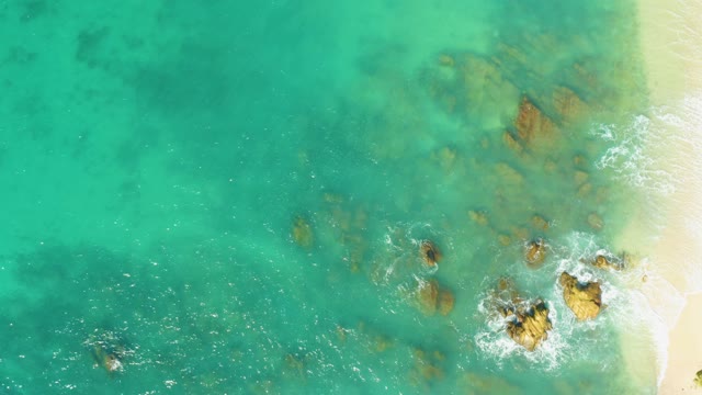 EL TULE BEACH LOS CABOS BCS MEXICO-2021: Waves Crashing Against Rocky Shore in Clear Water