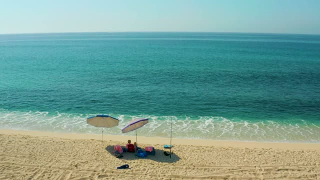 EL TULE BEACH LOS CABOS BCS MEXICO-2021: Beachgoers Relaxing Under Umbrellas by the Ocean