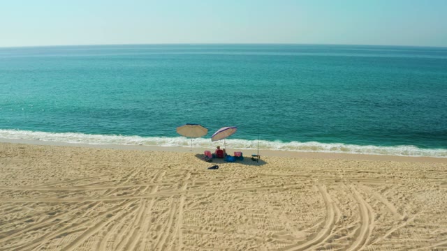 EL TULE BEACH LOS CABOS BCS MEXICO-2021: Beachgoer Relaxing Under Umbrella by Ocean