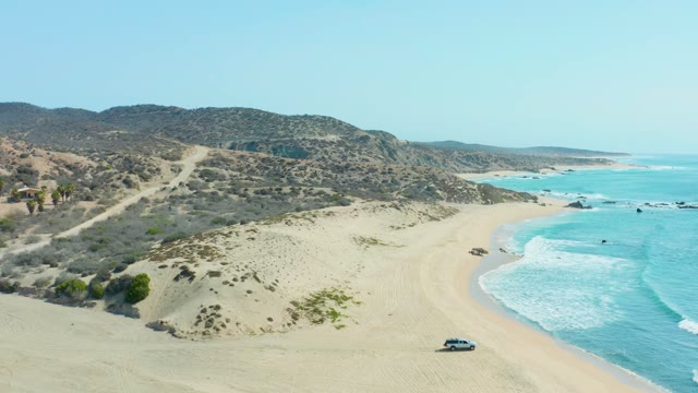 SAN LUIS BEACH EAST CAPE LOS CABOS MEXICO-2021: Car Driving Along Sandy Beach with Ocean Waves