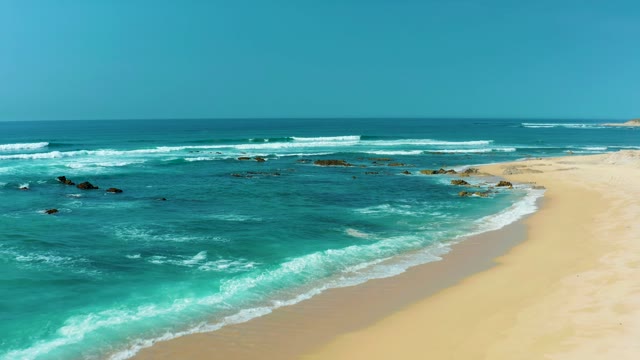 SAN LUIS BEACH EAST CAPE LOS CABOS MEXICO-2021: Waves Crashing on Sandy Shore with Rocky Outcrops