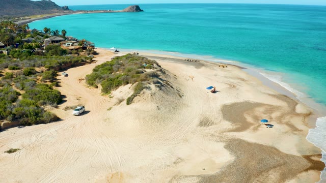 Aerial of White Vehicle Driving on Sandy Beach Dunes