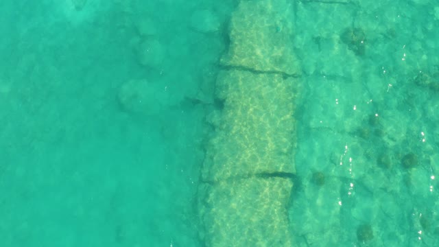 Fish Swimming near Submerged Stone Structure in Clear Turquoise Water