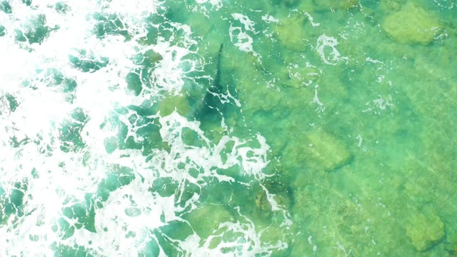 Waves Breaking over Clear Turquoise Water and Rocks