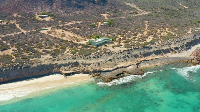Shifting Ocean Waves Along Sandy Beach and Rocky Cliffs