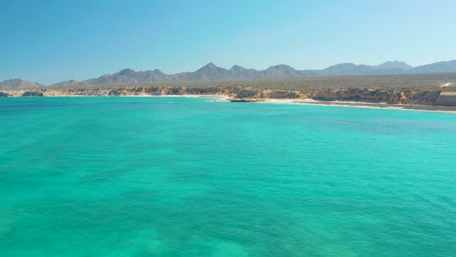 Turquoise Ocean Waters near Sandy Beach with Distant Mountains