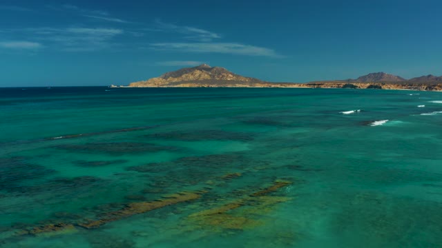 Gentle Ocean Waves and Distant Island in Turquoise Water