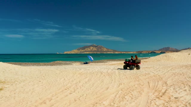 ATV Driving on Sandy Beach with Turquoise Ocean