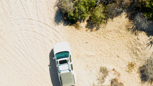 White Pickup Truck Moving on Sandy Terrain