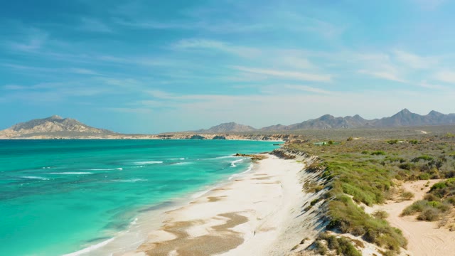 People Walking on a Sandy Beach with Clear Turquoise Water