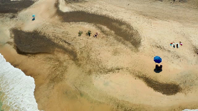 People and Bicycles Moving on Sandy Beach