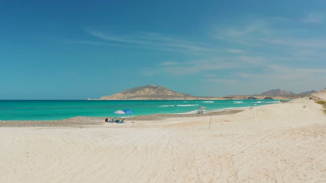 CABO PULMO BCS MEXICO-2021: Beachgoers Moving on Sandy Shore with Turquoise Ocean