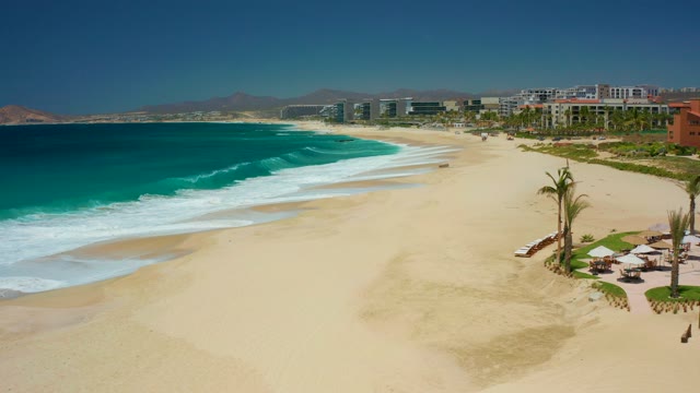 DREAMS LOS CABOS BCS MEXICO-2021: Waves Crashing on Sandy Beach with Coastal Buildings