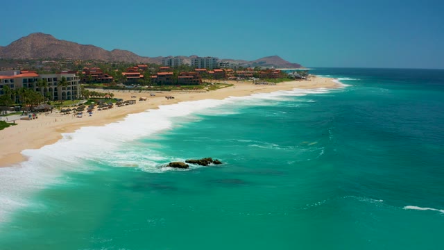 DREAMS LOS CABOS BCS MEXICO-2021: Waves Rolling Onto Sandy Shore with Coastal Buildings