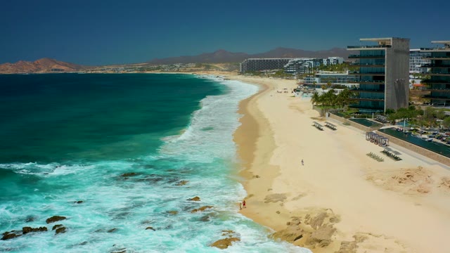 DREAMS LOS CABOS BCS MEXICO-2021: Waves Crashing on Sandy Beach with Coastal Buildings